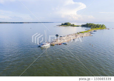Aerial view of the yachts moored at the sandy spit of the lake with the edges of the forest 133085339