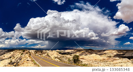 Utah State Route 12 winds over The Hogback in Grand Staircase-Escalante National Monument. A large, dramatic storm cloud with rain (virga) hangs over the vast slickrock landscape Utah State Route 12 winds over The Hogback in Grand Staircase-Escalante National Monument. A large, dramatic storm cloud with rain (virga) hangs over the vast slickrock landscape 133085348