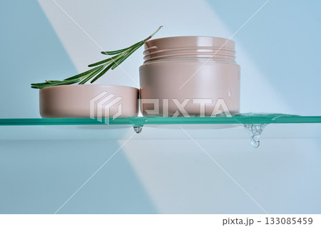 A jar of rosemary cream on the glass shelf of the bathroom. 133085459