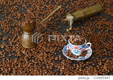 Turkish coffee concept. Copper pot (Cezve), vintage coffee grinder, coffee beans on a dark wooden background. 133085847