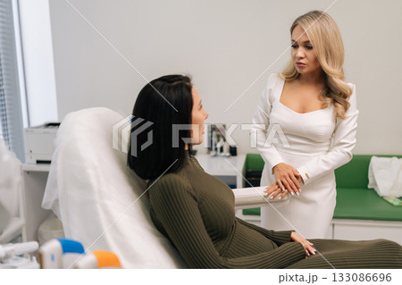Skilled beauty expert engaging in consultation about cosmetic treatment with woman in chair at contemporary aesthetic clinic, elaborating on specifics of procedure. Concept of facial anti-aging. Skilled beauty expert engaging in consultation about cosmetic treatment with woman in chair at contemporary aesthetic clinic, elaborating on specifics of procedure. Concept of facial anti-aging. 133086696