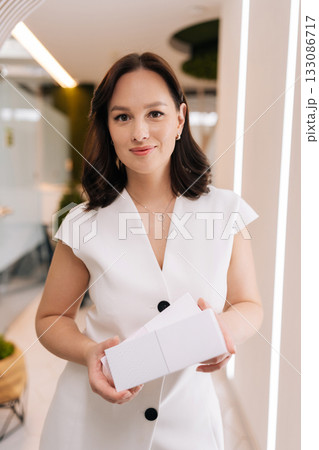 Professional female cosmetologist presenting blank cosmetic product boxes, symbolizing expertise and advertising in the beauty and healthcare industry. Concept of rejuvenating skin, preventing aging. Professional female cosmetologist presenting blank cosmetic product boxes, symbolizing expertise and advertising in the beauty and healthcare industry. Concept of rejuvenating skin, preventing aging. 133086717