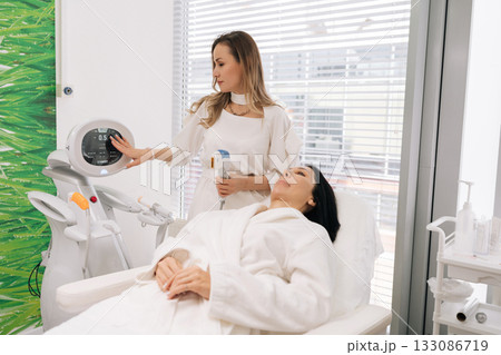 Portrait of cosmetic doctor performing mesotherapy microneedling on woman face, providing skin rejuvenation and professional cosmetic care in clinic. Concept of facial anti-aging, skincare treatment. 133086719