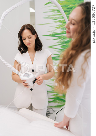 Beautician doctor preparing client for hardware cosmetology procedure, utilizing advanced skin lifting technology for facial and body aesthetic medicine treatments. Concept of healthy lifestyle. 133086727