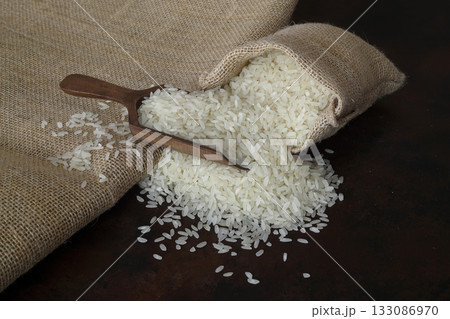 Bag with long rice and spoon stands on wooden background Bag with long rice and spoon stands on wooden background 133086970