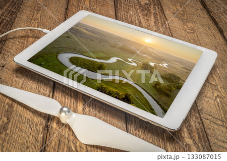 sunrise over a river meandering through Nebraska Sandhills - reviewing aerial image of Middle Loup RIver on a digital tablet 133087015