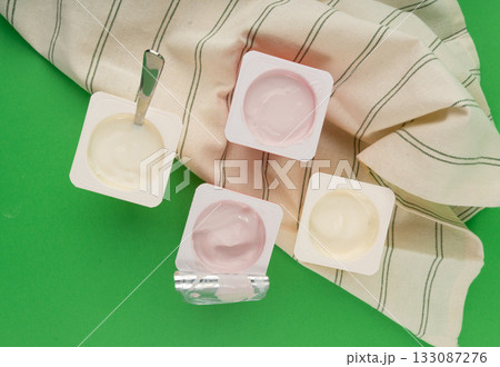 Yogurt cups set, pink and yellow fruit yoghurt in plastic pots, milk pudding container with spoon Yogurt cups set, pink and yellow fruit yoghurt in plastic pots, milk pudding container with spoon 133087276