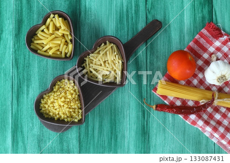 Italian Food background on green table Top view. With heart shaped bowl Italian Food background on green table Top view. With heart shaped bowl 133087431