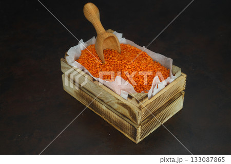 Red Lentil in a small wooden crate, isolated on dark background. With Wooden Spoon. 133087865