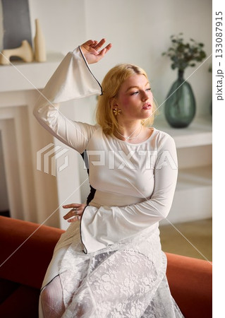 Sunlit interior showcases woman in lace skirt with calm smile Sunlit interior showcases woman in lace skirt with calm smile 133087915