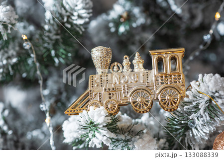 Golden Train Ornament on Snow-Flocked Christmas Tree 133088339