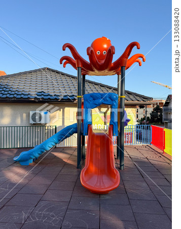 Playground slide with octopus decoration. Childhood, fun, and outdoor leisure in colorful urban environment. 133088420