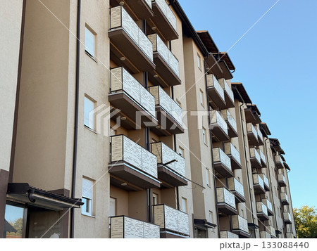 Modern apartment building with balconies and clear blue sky. Architecture, urban development, and residential housing design. Modern apartment building with balconies and clear blue sky. Architecture, urban development, and residential housing design. 133088440