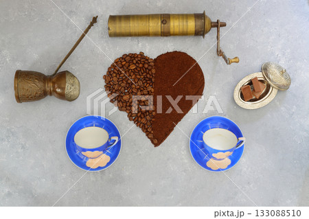 Coffee beans and ground coffee in wooden spoons on brown background. With pot, cup and grinder Coffee beans and ground coffee in wooden spoons on brown background. With pot, cup and grinder 133088510