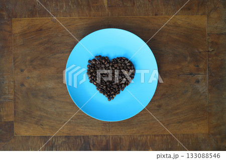 Roasted coffee beans in heart shaped bowl on dark background. Love coffee concept. Top view flat lay with copy space 133088546