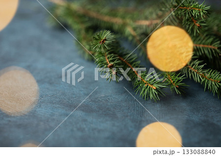 Fir branches and Christmas lights with a bokeh effect on a dark blue background Fir branches and Christmas lights with a bokeh effect on a dark blue background 133088840