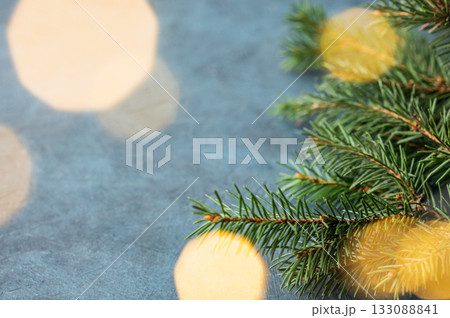 Fir branches and Christmas lights with a bokeh effect on a dark blue background Fir branches and Christmas lights with a bokeh effect on a dark blue background 133088841