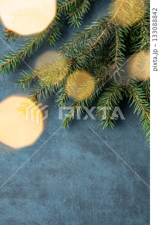 Fir branches and Christmas lights with a bokeh effect on a dark blue background Fir branches and Christmas lights with a bokeh effect on a dark blue background 133088842