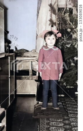 Vintage portrait of a cute little girl by the Christmas tree. Retro photo from 1972. Vintage portrait of a cute little girl by the Christmas tree. Retro photo from 1972. 133089016