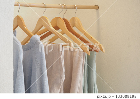 Soft clothing hanging on wooden hangers in a closet 133089198