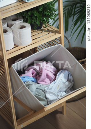 Laundry basket filled with colorful clothes in a cozy room 133089210