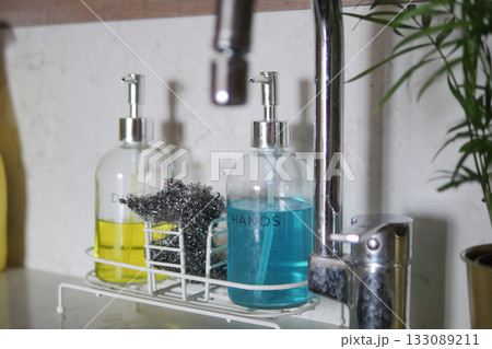 Soap dispensers on a kitchen counter with steel scrubber 133089211