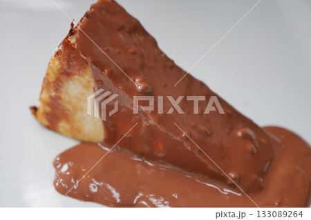 A slice of cheese cake topped with rich chocolate sauce. 133089264