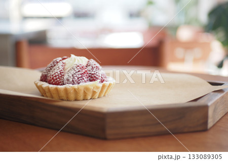 Delicious strawberry tart on a wooden tray in a cozy cafe Delicious strawberry tart on a wooden tray in a cozy cafe 133089305