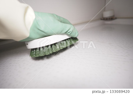 Cleaning a toilet surface with a green brush in a bright space Cleaning a toilet surface with a green brush in a bright space 133089420