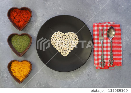 white kidney beans in a heart shaped black plate a on white background. Top view. 133089569