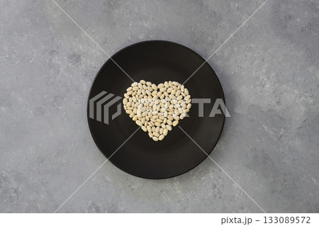 white kidney beans in a heart shaped black plate a on white background. Top view. 133089572