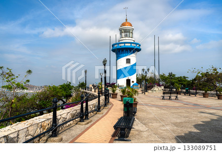 View of the blue and white lighthouse on Santa Ana Hill in Guayaquil, Ecuador. The viewpoint overlooks the city under a blue sky with clouds View of the blue and white lighthouse on Santa Ana Hill in Guayaquil, Ecuador. The viewpoint overlooks the city under a blue sky with clouds 133089751