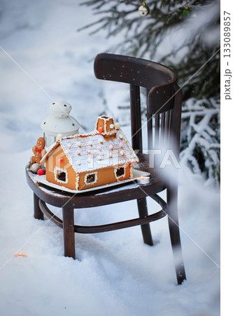 Gingerbread house and holiday decoration on chair in snow winter outdoor background Gingerbread house and holiday decoration on chair in snow winter outdoor background 133089857