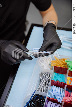 Orthodontic elastics and power chains selected with pliers in dental clinic, closeup 133089993