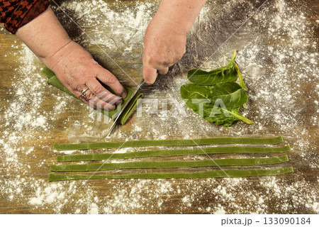Hands cutting purple noodles with ingredients on the table, homemade italian food. 133090184