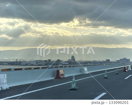 関西国際空港連絡橋から見る厚い雲の隙間から漏れる朝の光の筋と遠くに見える山並み 関西国際空港連絡橋から見る厚い雲の隙間から漏れる朝の光の筋と遠くに見える山並み 133090201