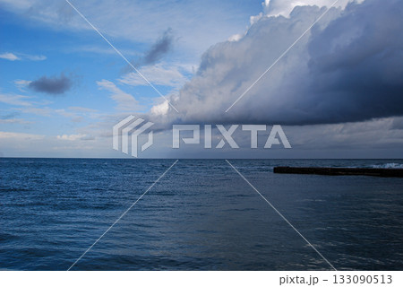 Dramatic ocean view with approaching storm clouds. Expansive sea view under a sky filled with thick, dark storm clouds approaching from the right.  133090513