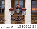 Ornate street lamp with ironwork in front of classic building columns 133091383