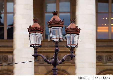 Ornate street lamp with ironwork in front of classic building columns Ornate street lamp with ironwork in front of classic building columns 133091383