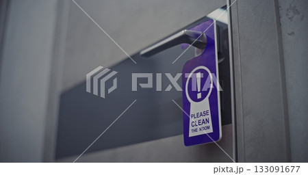 Female Hotel Guest Exits Room and Places Please Clean Room Sign on Door Handle 133091677