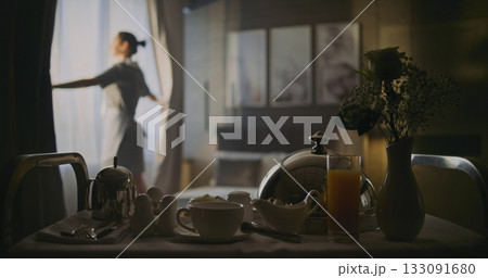 Professional Hotel Maid Opens Curtains on Windows and Makes Fresh, Neat Bed in Elegant Room Professional Hotel Maid Opens Curtains on Windows and Makes Fresh, Neat Bed in Elegant Room 133091680