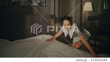 Cheerful Female Maid in Professional Hotel Uniform Smooths Perfectly Fresh Bedding on Large Bed Cheerful Female Maid in Professional Hotel Uniform Smooths Perfectly Fresh Bedding on Large Bed 133091689