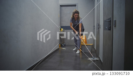 Hotel Housekeeper in Grey Uniform Mopping Hallway Floor Hotel Housekeeper in Grey Uniform Mopping Hallway Floor 133091710