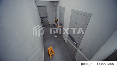Hotel Cleaning Staff in Neat Uniform Thoroughly Cleans Door With Gentle Cloth and Disinfectant 133091800