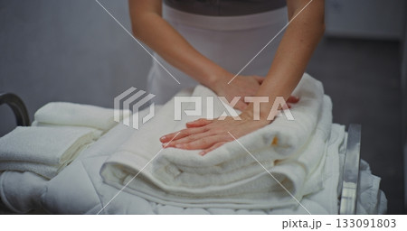 Maid in Uniform Attentively Sorting and Folding Towels on Trolley in Modern Hotel Corridor Maid in Uniform Attentively Sorting and Folding Towels on Trolley in Modern Hotel Corridor 133091803