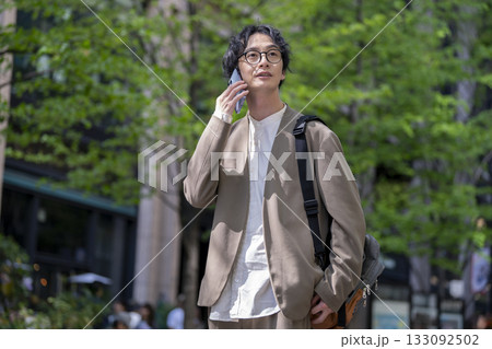 街の中でスマートフォンで通話をする30代の男性 街の中でスマートフォンで通話をする30代の男性 133092502