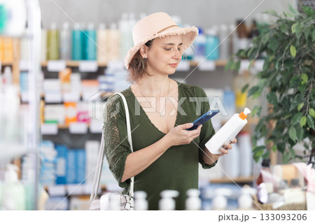 Woman in pharmacy scans QR code on sunscreen cream 133093206