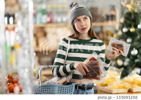 Wwoman with a basket of groceries buys dried jamon in supermarket 133093208