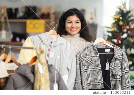 Woman chooses coat or jacket for the winter period in fashionable clothing store Woman chooses coat or jacket for the winter period in fashionable clothing store 133093211