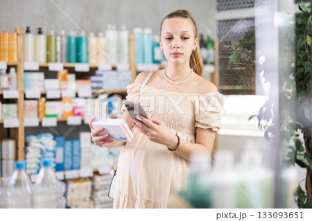 Pregnant woman in pharmacy scans QR code tablet medication product 133093651